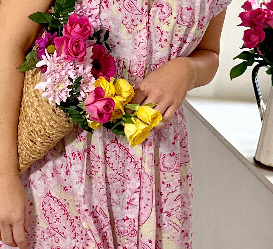 Rosehip Design Olivia is a beautiful cotton dress in our stylish pink and yellow Paisley Rhubarb print. The Olivia dress has short, capped sleeves with a rough frill. The skirt is tiered and has pockets.