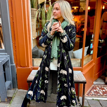 Wrap yourself in autumn warmth with this long velvet coat in a rich Rosehip Design Winter Floral that perfectly echoes the season. The beautiful plum tones on navy blue are perfect for this time of year. The soft velvet exterior is complemented by a classic check lining, adding a touch of style to its bold, modern silhouette. Luxuriously warm yet effortlessly wearable, it’s the perfect layer for crisp autumn days — whether you’re strolling through the countryside or heading into the city.