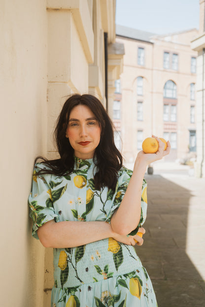 The Rosehip Design Hannah Cotton Shirt in Citrus Blue is a timeless blend of elegance and comfort. Made from soft cotton, it features a delicate frilled collar and intricate smocking on the sleeves for a touch of vintage charm. Designed for effortless styling, it pairs beautifully with the Bella Skirt