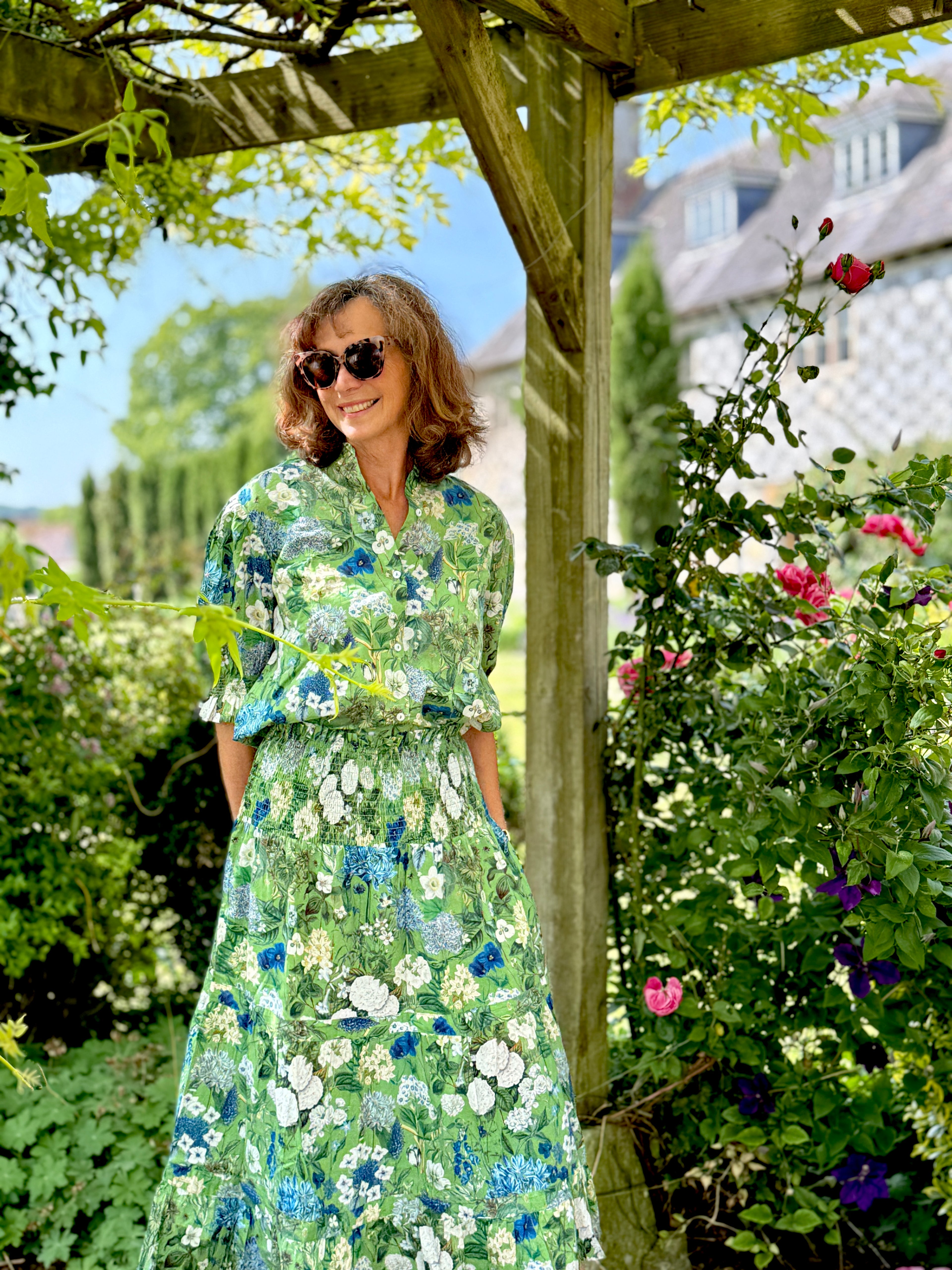 Rosehip Design Hannah Cotton Shirt in Spring Greens is a timeless blend of elegance and comfort. Made from soft cotton, it features a delicate frilled collar and intricate smocking on the sleeves for a touch of vintage charm. Designed for effortless styling, it pairs beautifully with the matching Bella Skirt.