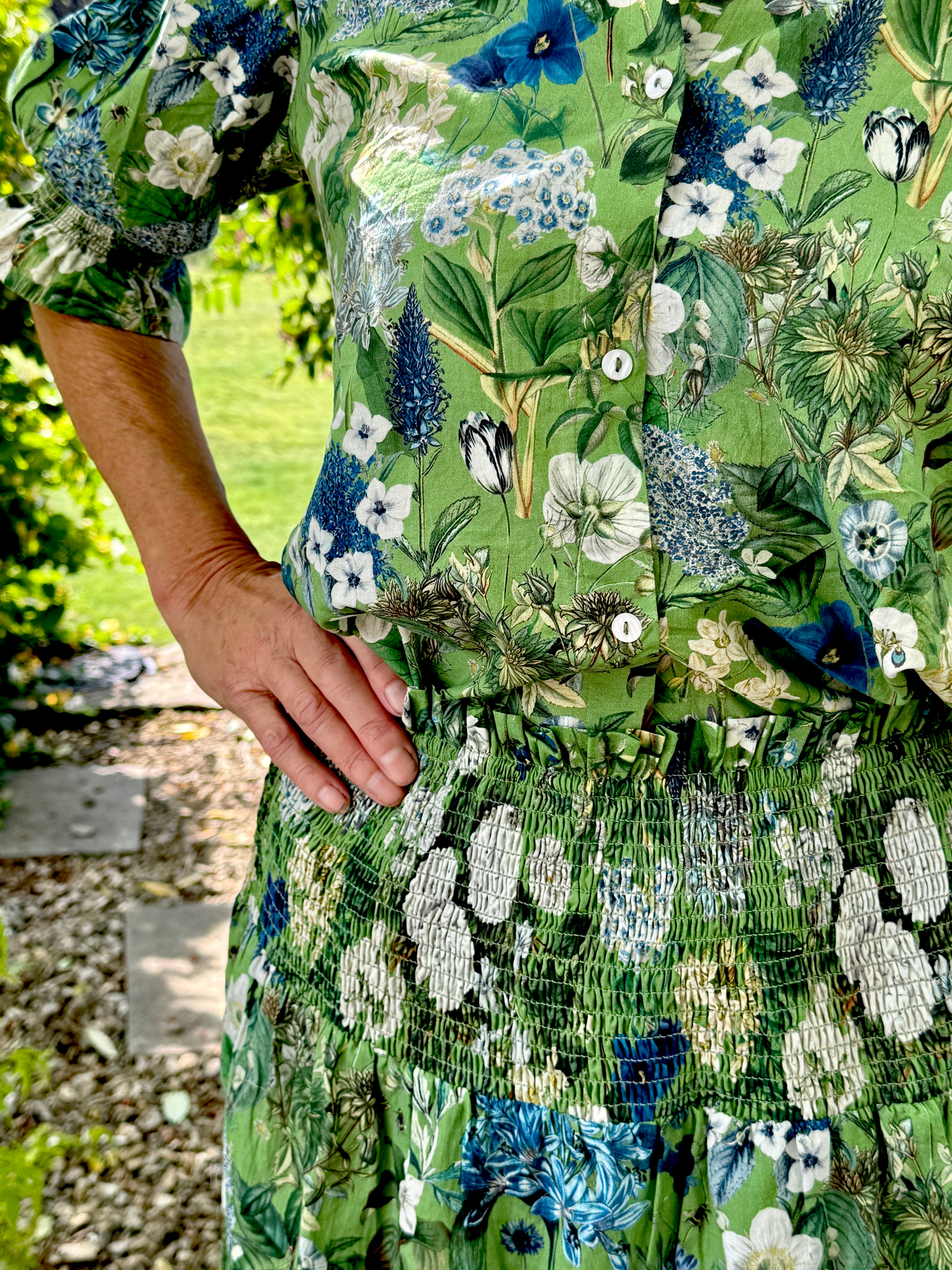 Rosehip Design Hannah Cotton Shirt in Spring Greens is a timeless blend of elegance and comfort. Made from soft cotton, it features a delicate frilled collar and intricate smocking on the sleeves for a touch of vintage charm. Designed for effortless styling, it pairs beautifully with the matching Bella Skirt.