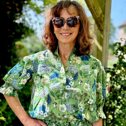 Rosehip Design Hannah Cotton Shirt in Spring Greens is a timeless blend of elegance and comfort. Made from soft cotton, it features a delicate frilled collar and intricate smocking on the sleeves for a touch of vintage charm. Designed for effortless styling, it pairs beautifully with the matching Bella Skirt.