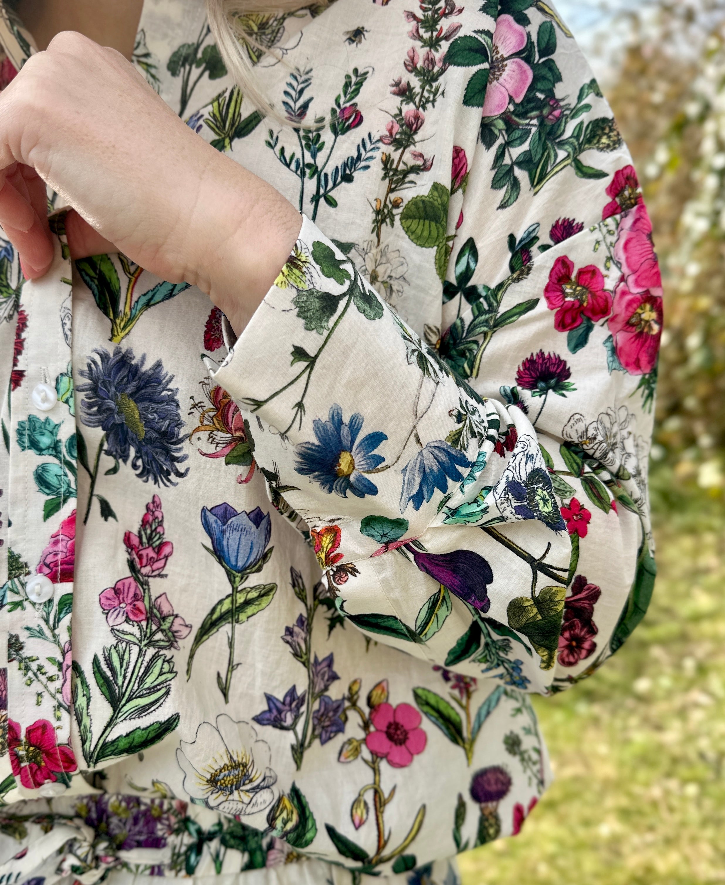 The Rosehip Design Sarah Cotton Shirt is a timeless wardrobe staple, made of soft cotton. It features a classic button-down front, elegant sleeves that end just before the wrist, and a gently curved hem for a relaxed yet polished look.

Featuring our vibrant Barcelona print, this shirt is a celebration of summer, bursting with lively hues and intricate floral patterns. Perfect for warm-weather styling, it pairs beautifully with the matching Sally Skirt for a coordinated ensemble, or just jeans.