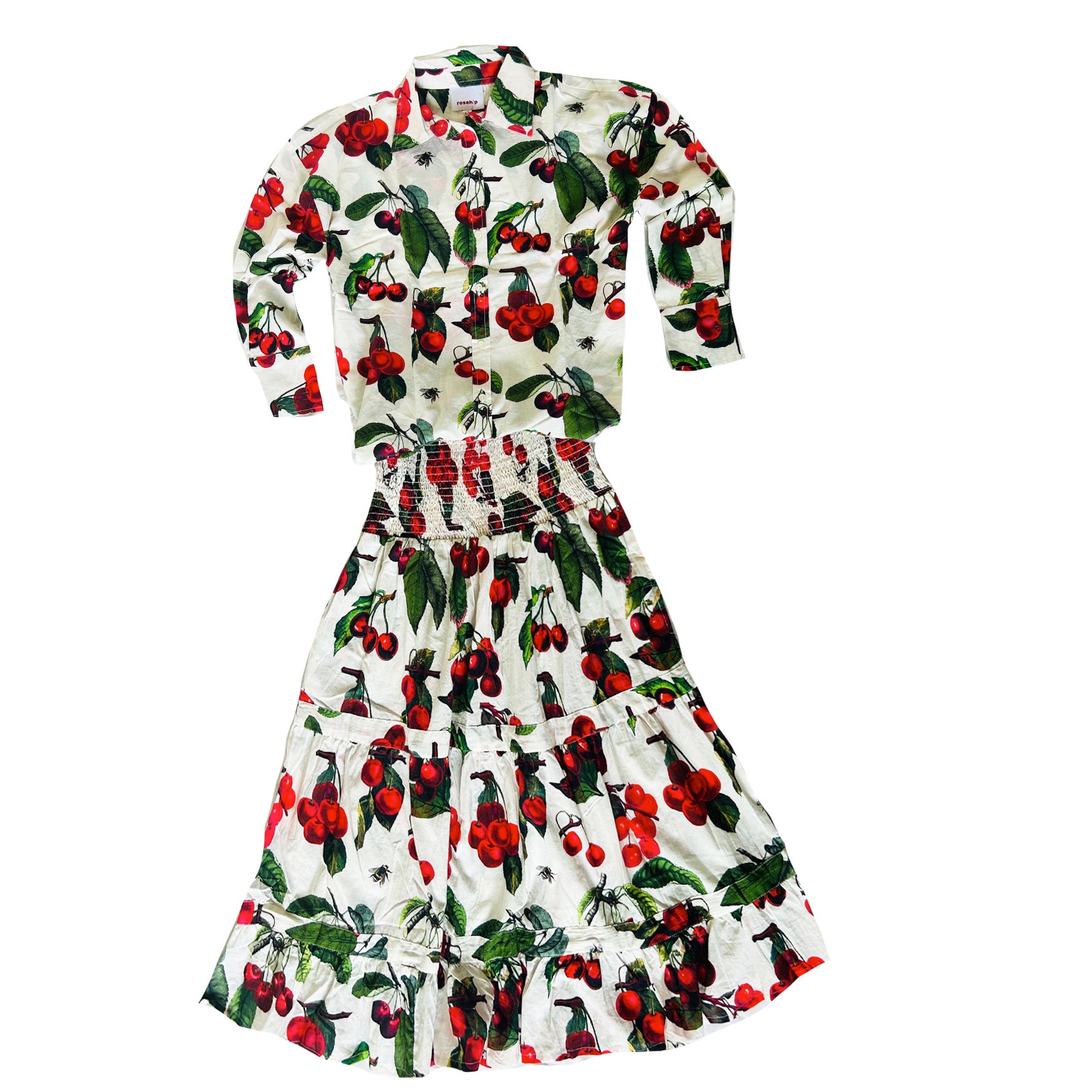 Rosehip Design Sarah Cotton Shirt is a timeless wardrobe staple, made of soft cotton. Featuring a classic button-down front, elegant sleeves that end just before the wrist, and a gently curved hem for a relaxed yet polished look. 

The edible Cherries print is a celebration of summer, bursting with lively hues and intricate floral patterns. Perfect for warm-weather styling, it pairs beautifully with the matching Sally Skirt for a coordinated ensemble or can be effortlessly styled with jeans or shorts.