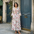 Woman in a Rosehip floral dress standing in front of a building with wisteria