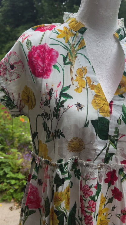 Rosehip Design Olivia is a beautiful cotton dress in our cheerful Corsley floral print. The Olivia dress has short, capped sleeves with a rough frill. The skirt is tiered and has pockets.